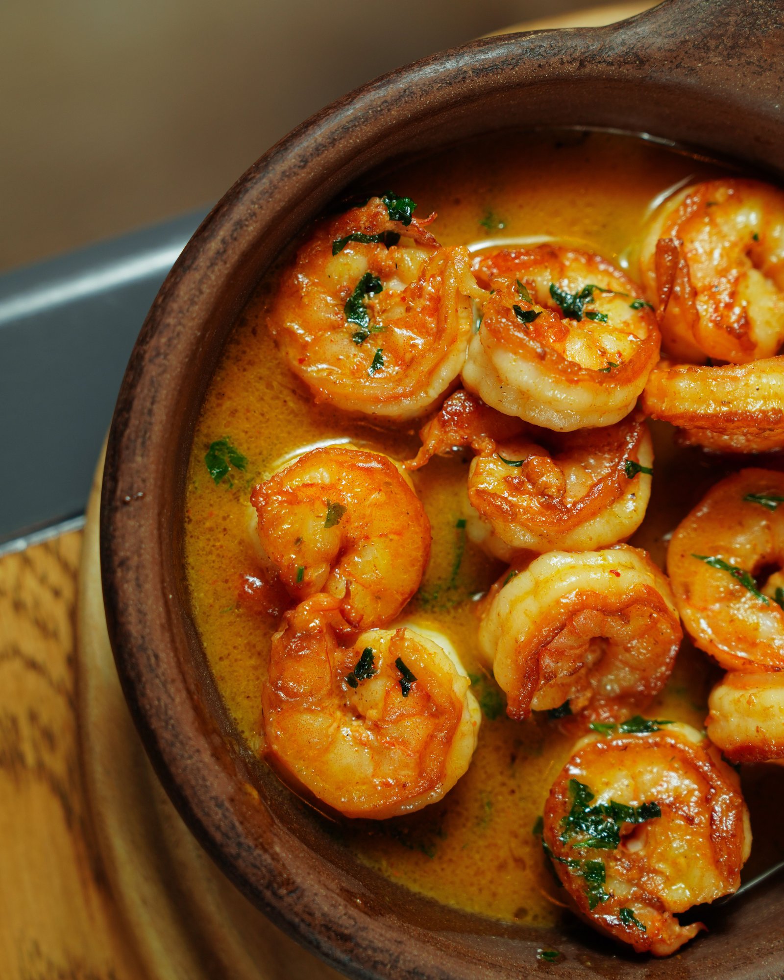 Spicy Garlic Shrimp: A Bold and Flavorful Seafood Favorite Spicy garlic shrimp coated in a rich orange sauce with fresh herbs, served in a rustic brown bowl.