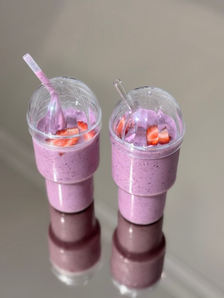 Easy Strawberry Smoothie Recipe for a Fresh and Creamy Drink Two creamy strawberry smoothies in clear dome-lid cups topped with sliced strawberries